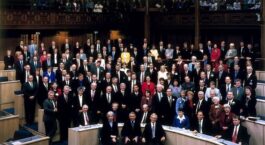 Grote groep politici poseert in een parlementaire vergaderzaal