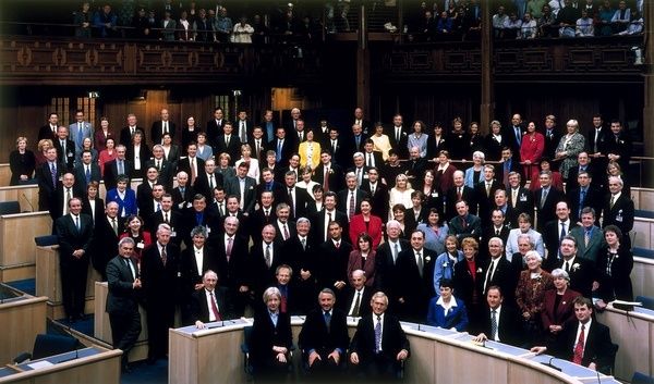 Grote groep politici poseert in een parlementaire vergaderzaal