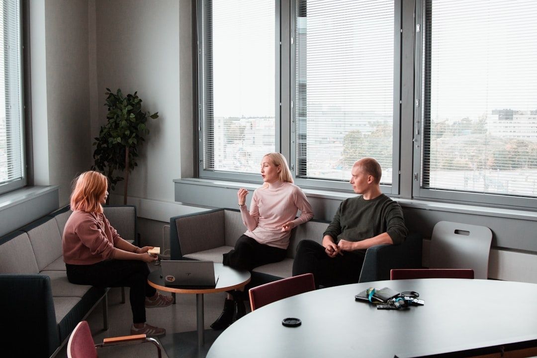 Drie mensen overleggen in een lichte kantoorruimte rond een tafel