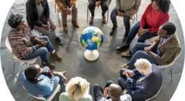 Diverse groep mensen bespreekt een wereldbol tijdens een burgerberaad